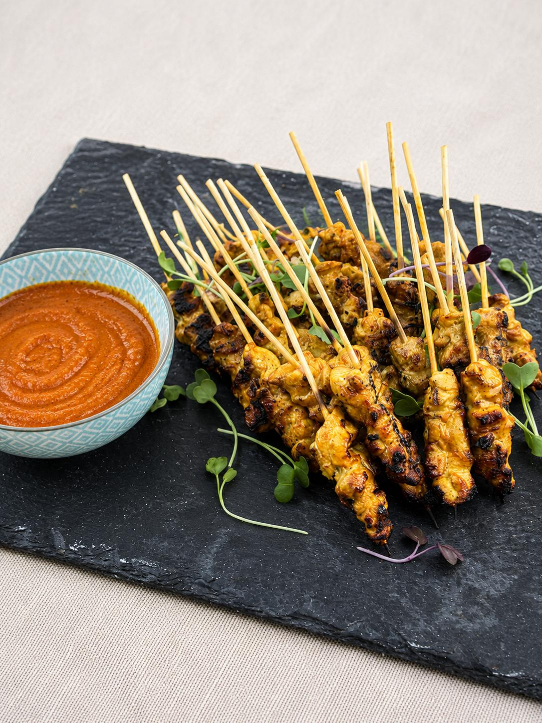 Malaysian chicken skewers with satay sauce on a slate platter