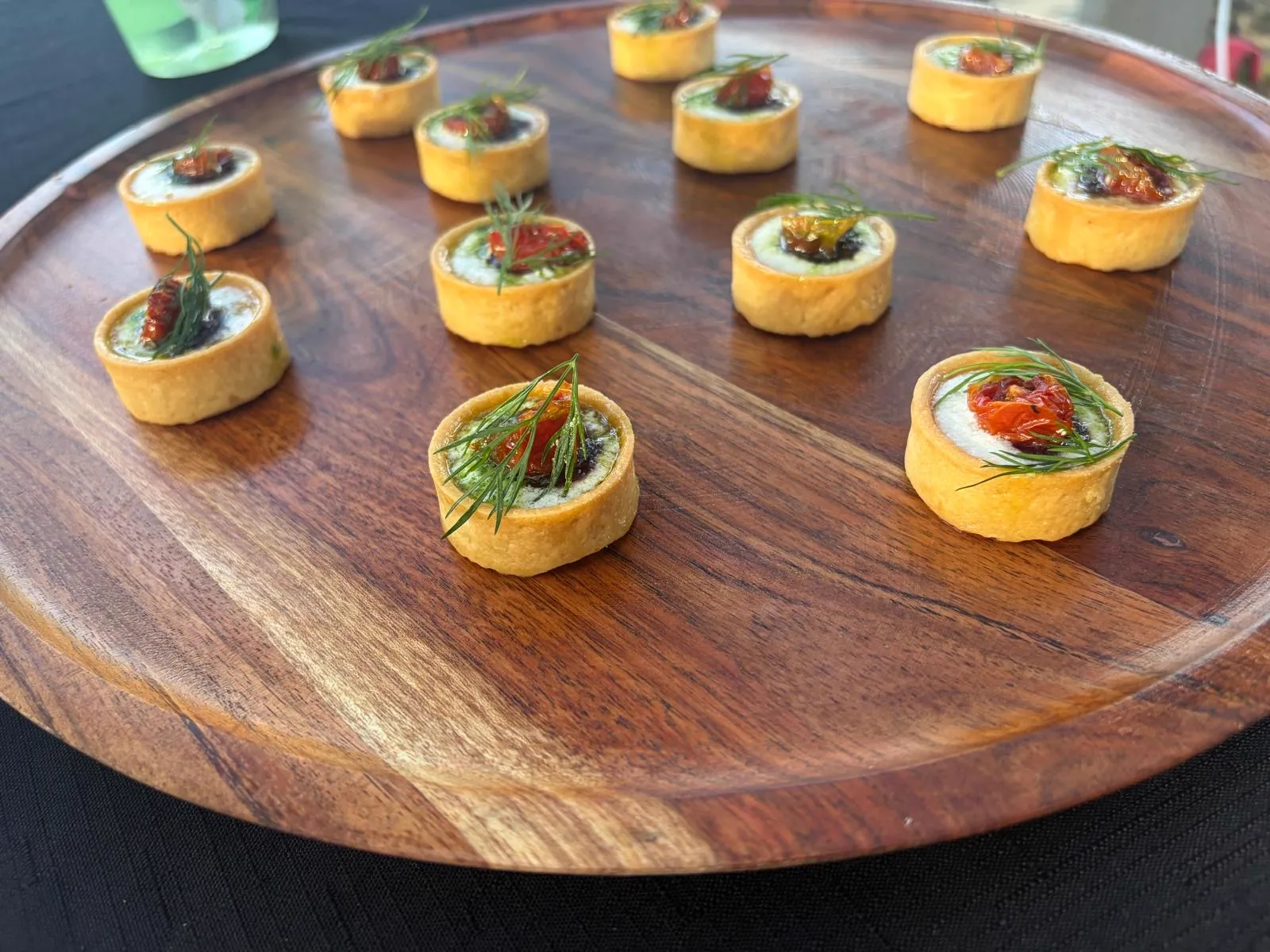 Goat's cheese tartlets set out on a round timber board