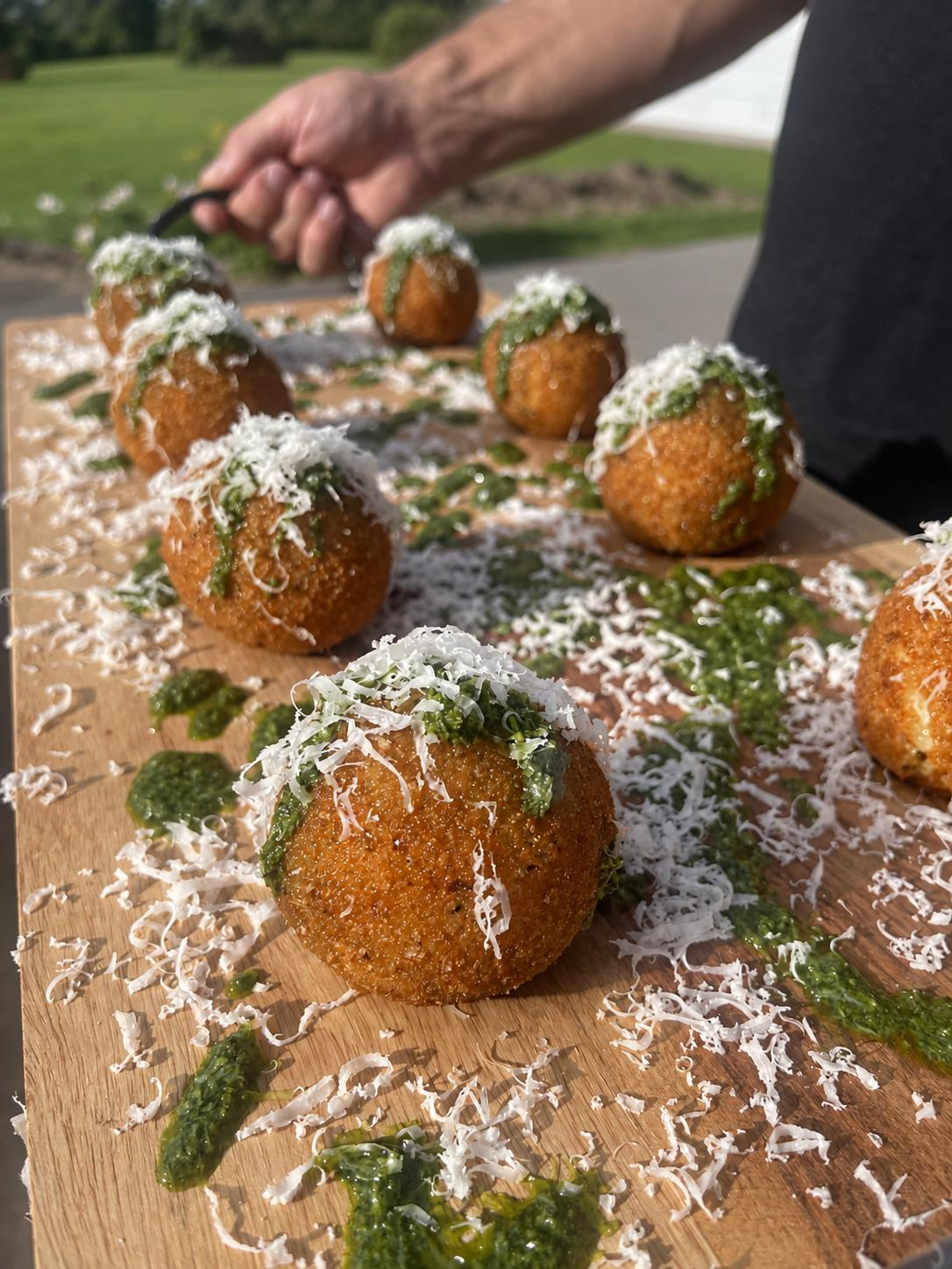 Classic bolognese arancini on a timber board with salsa verde