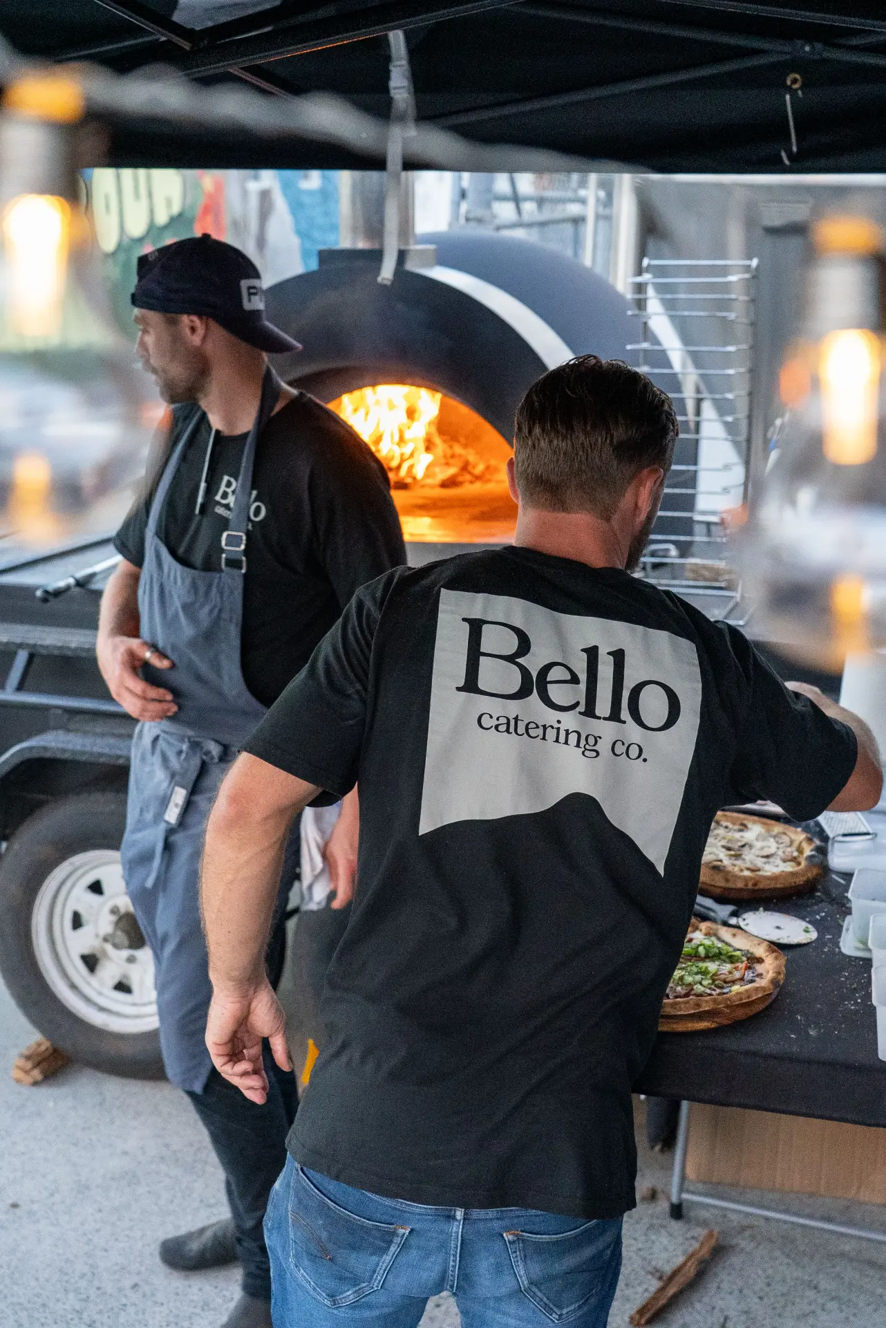 Bello team firing pizzas at the wood-fired oven on site