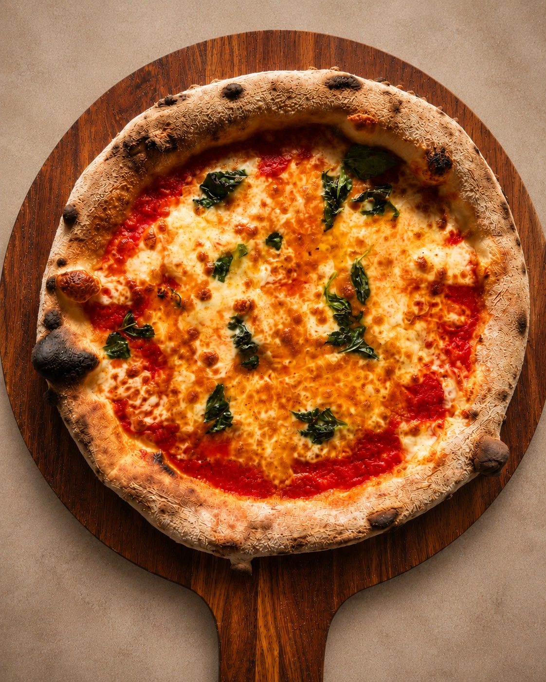 Wood-fired Margherita pizza with basil on a timber peel