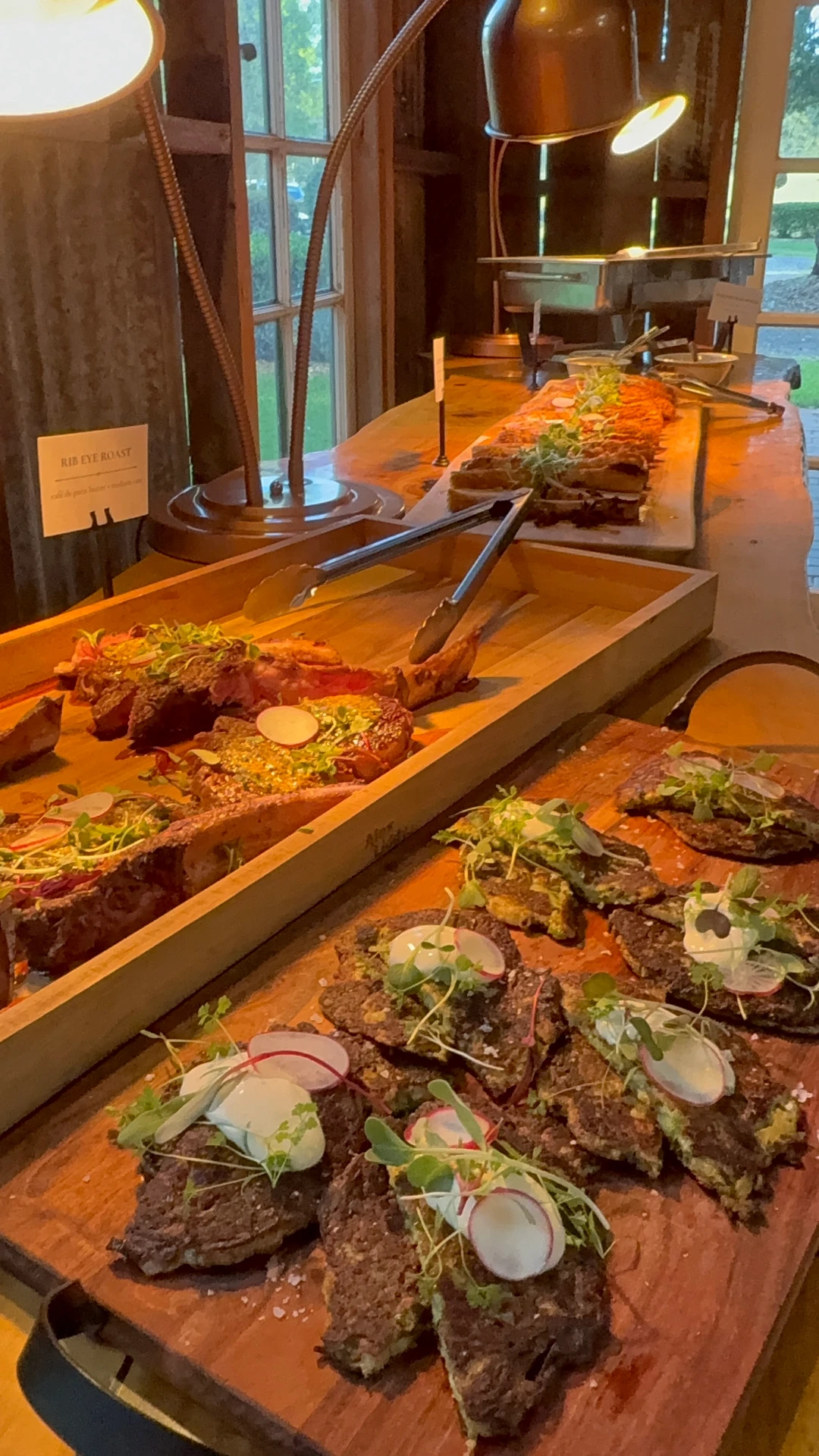 Shared banquet board of fire-roasted meats under warm heat lamps