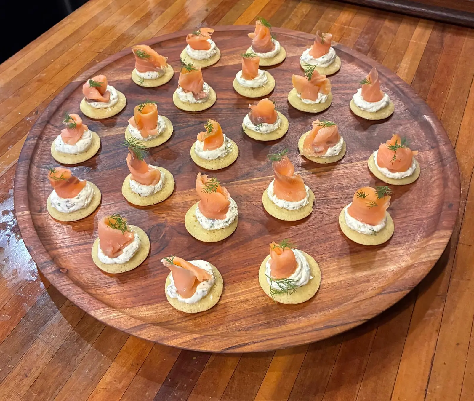Smoked salmon blinis with dill on a round timber board